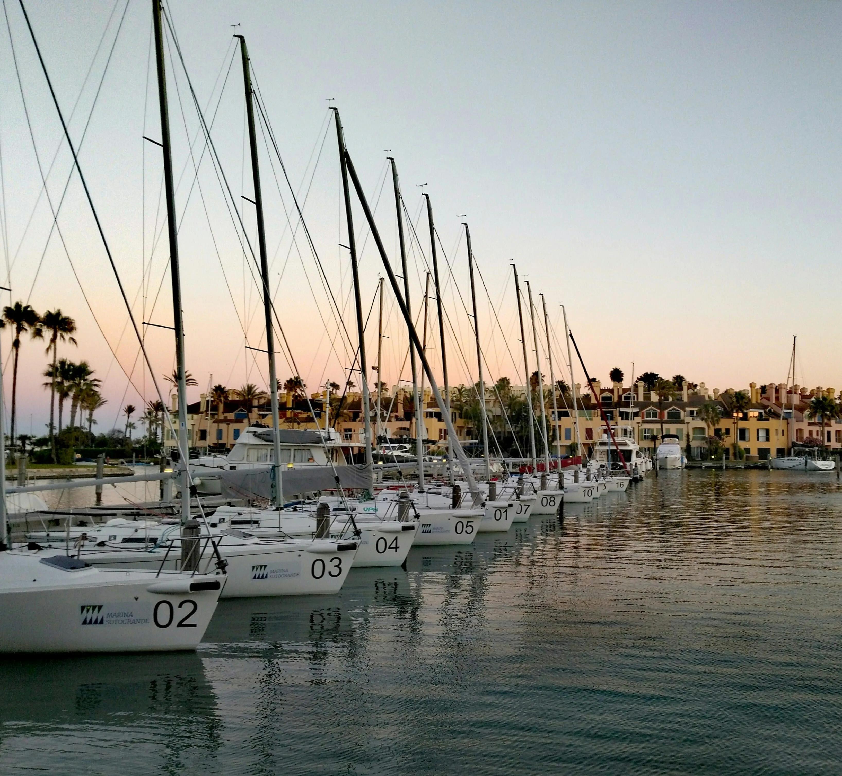 Marina de Sotogrande at dusk, moored yachts along the waterside houses